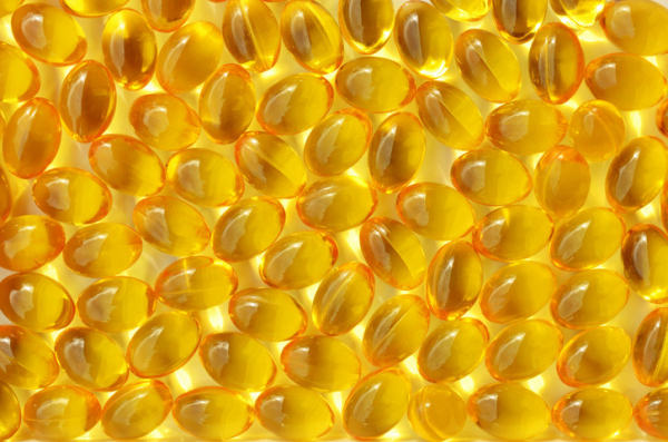 Close up of soft gel vitamin D capsules on a yellow background